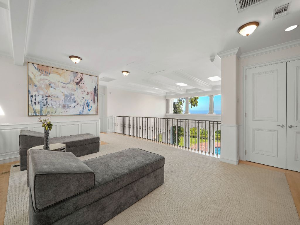 Een ruime woonkamer met een grijze modulaire bank, een groot abstract schilderij en een balkon met uitzicht.