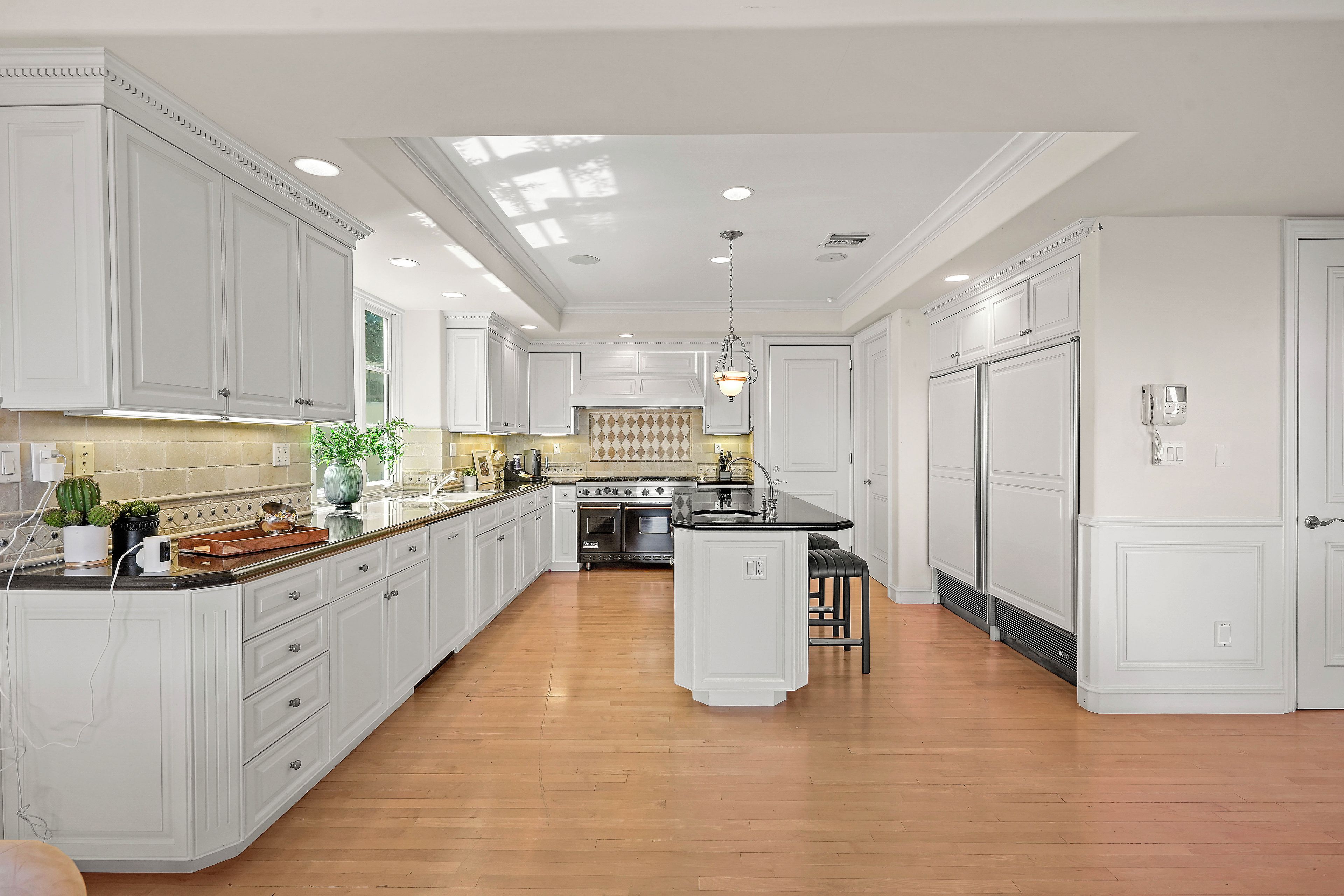A spacious kitchen with white cabinetry, a central island, and a built-in oven.