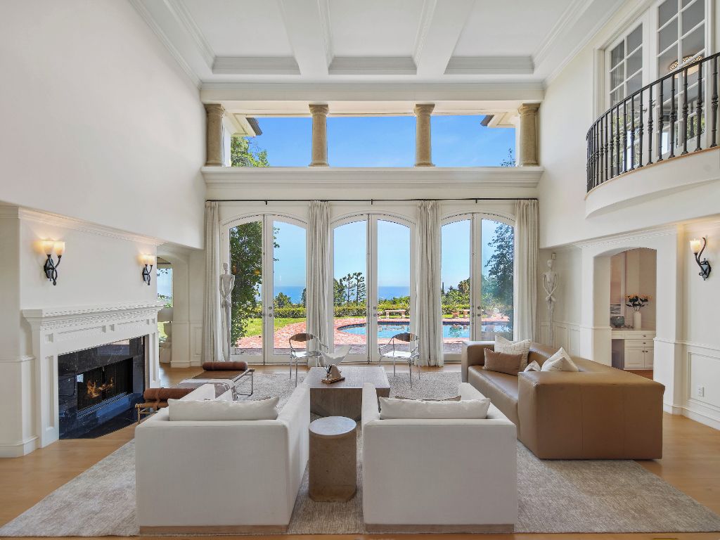 Un salón amplio con chimenea, ventanas grandes y vista a la piscina.