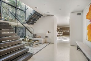 Un interior moderno con una escalera, un sofá, una mesa de centro y una zona de comedor.