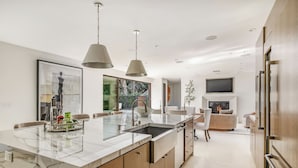 A modern kitchen with a marble island, pendant lights, and a built-in fireplace. - Laurel Canyon (Los Angeles)