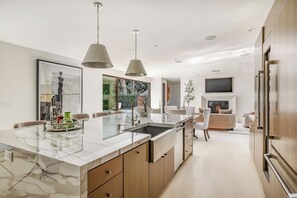 Uma cozinha moderna com ilha de mármore, luminárias pendentes e lareira embutida.