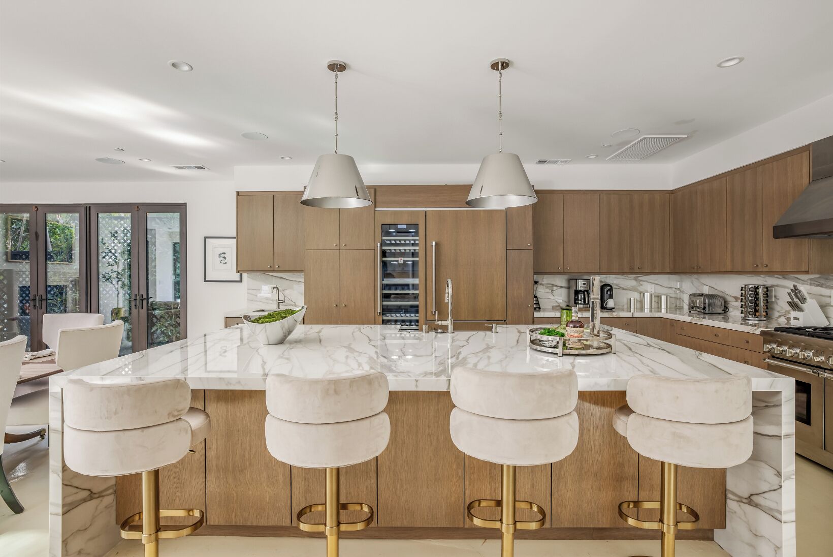 A modern kitchen with a marble countertop, wooden cabinets, and a central island with bar stools.