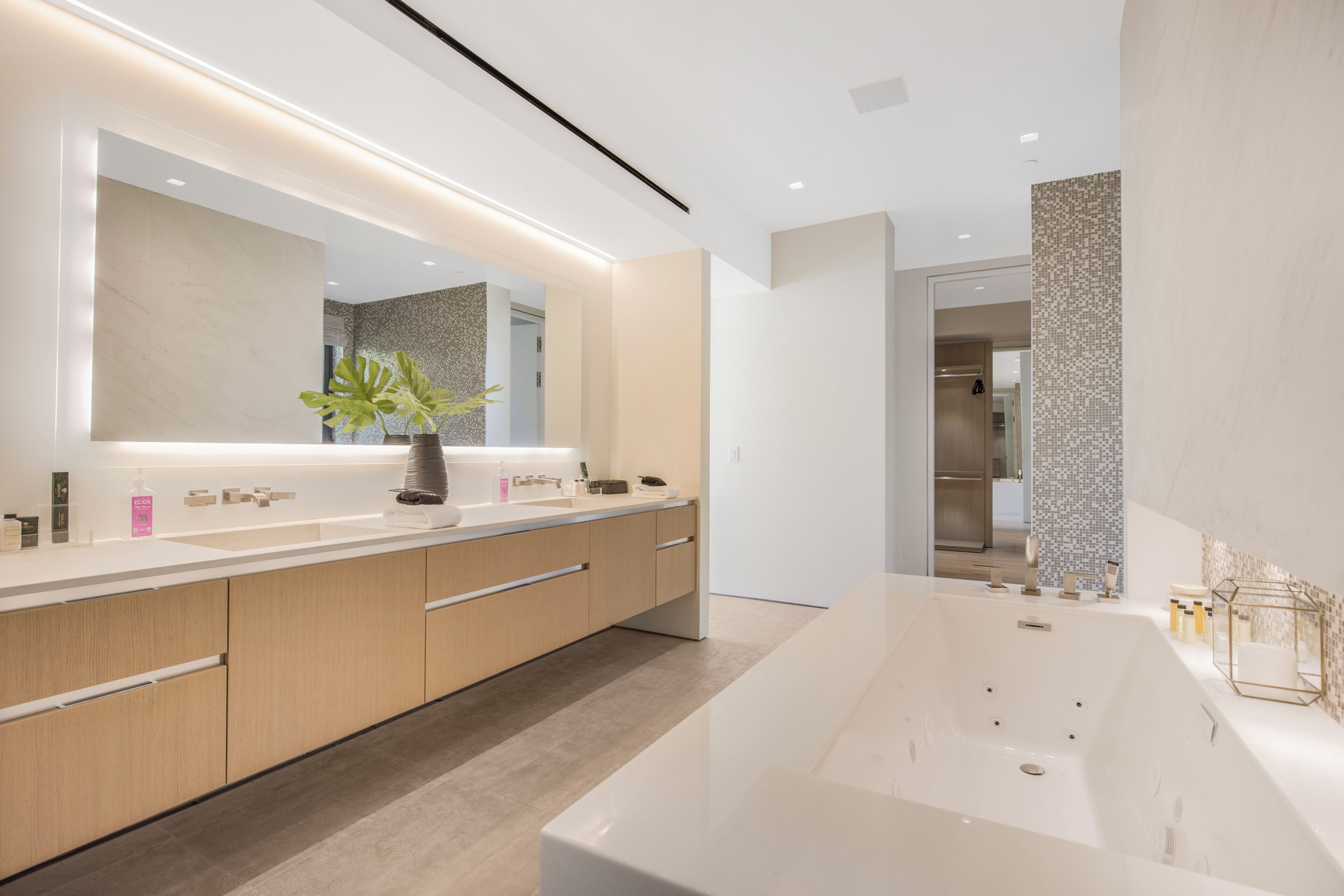 Une salle de bain moderne avec un grand miroir, une baignoire et un lavabo.
