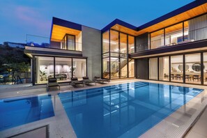 A modern house with a swimming pool, large glass windows, and a staircase leading to an upper level. - Swallow Sanctuary (West Hollywood)