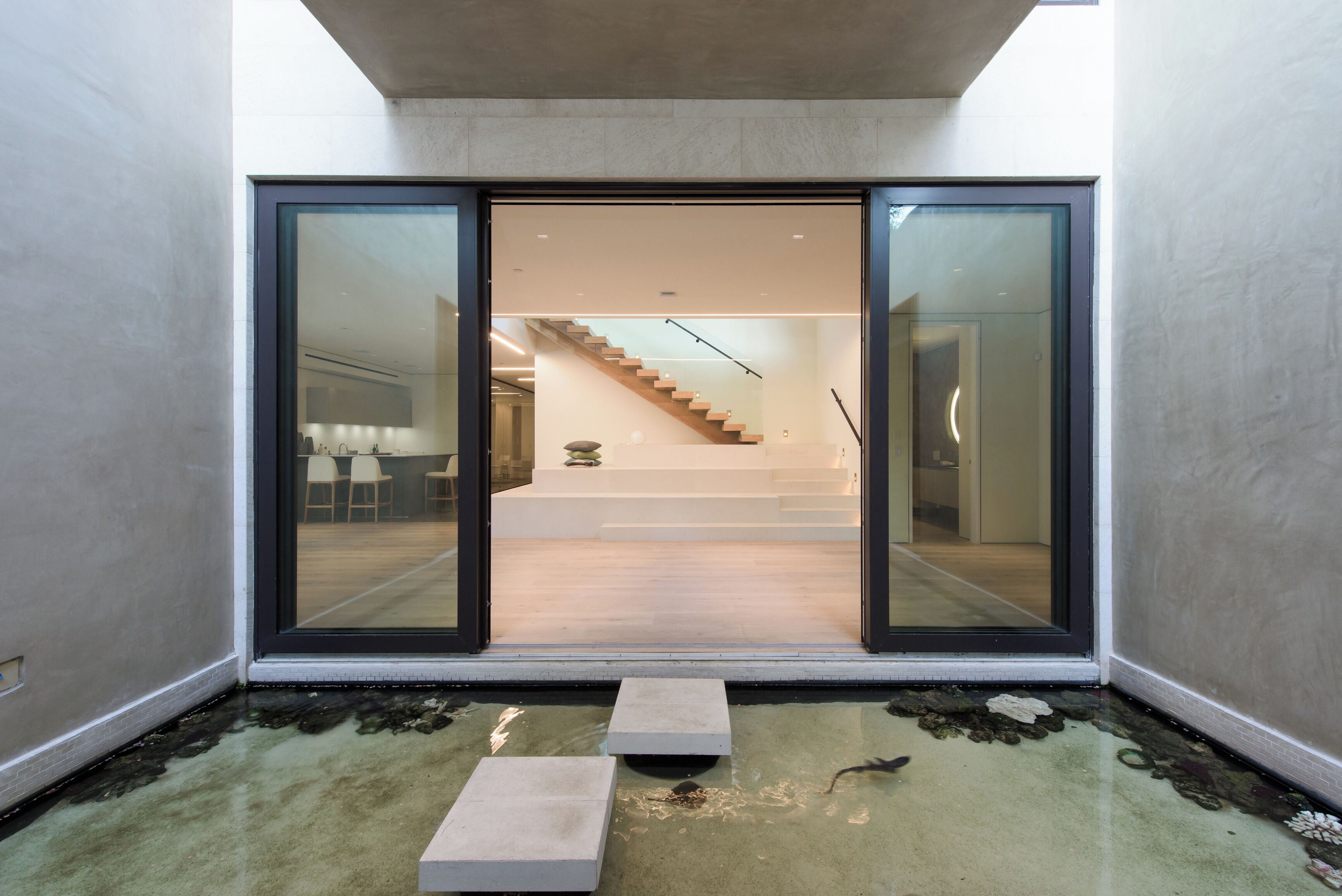 A modern interior with a glass door leading to a staircase and a dining area.