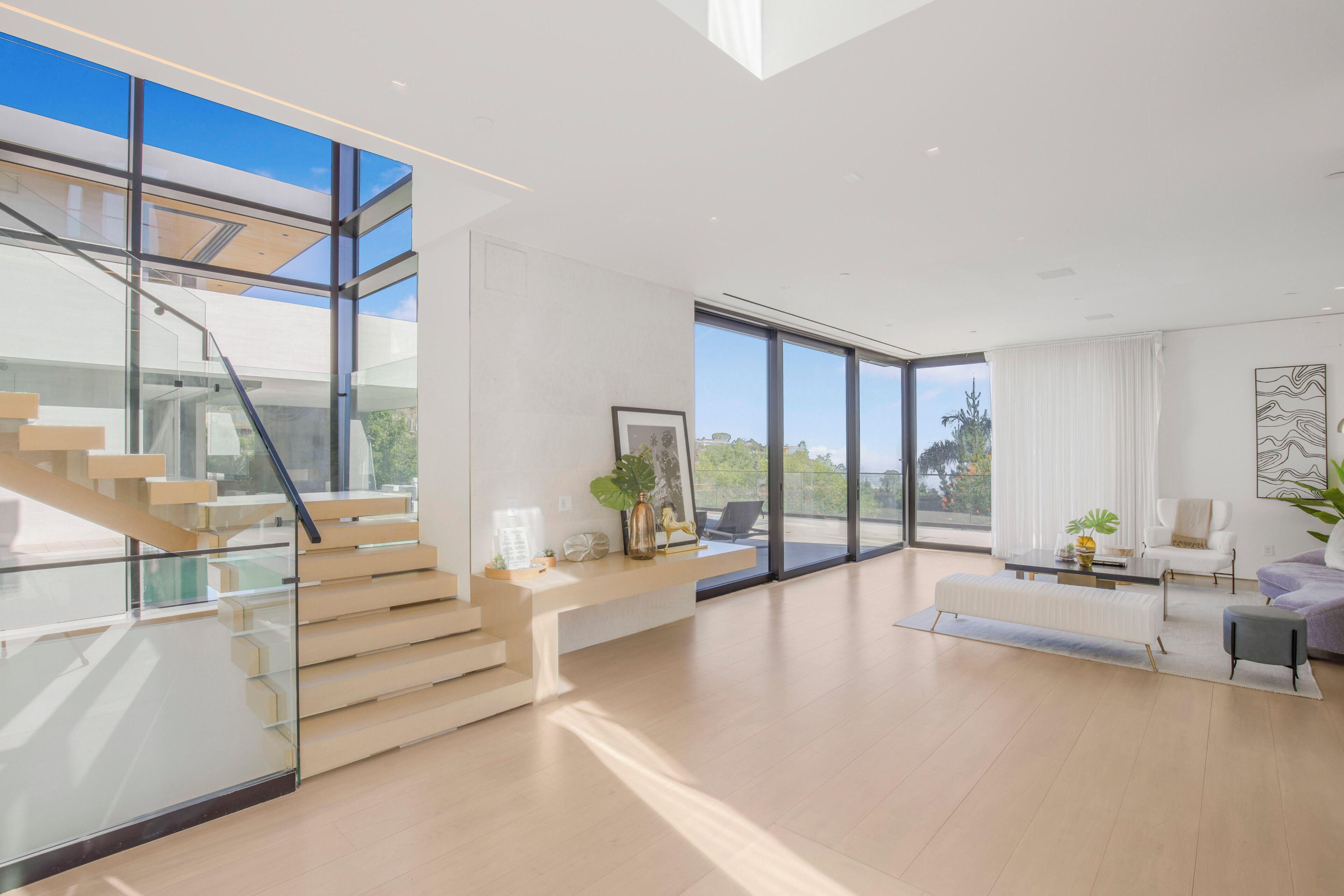 Uma sala de estar moderna com escada, janelas amplas e vista para o exterior.