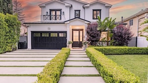 A two-story house with a garage, a front porch, and a well-maintained lawn. - Otis Ave (Tarzana)