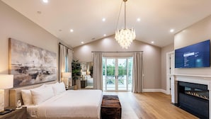 A spacious bedroom with a large bed, a fireplace, and a television. - Otis Ave (Tarzana)