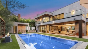 A modern house with a swimming pool, outdoor furniture, and a well-maintained garden.