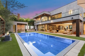 Una casa moderna con piscina, muebles de jardín y un jardín bien cuidado.