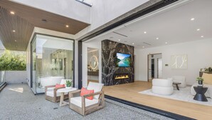 A modern hotel lobby with a fireplace, seating area, and a large TV screen.