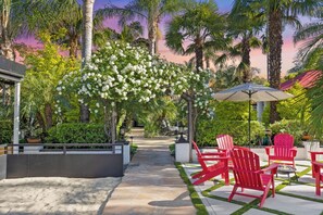 A patio area with red chairs, a pathway, and a white flowering tree. - Erwin Estate (Woodland Hills)