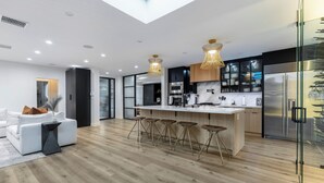 Une cuisine moderne dotée d’un îlot central, de tabourets de bar et d’un réfrigérateur à porte vitrée.