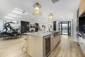 A modern kitchen with a central island, pendant lighting, and a dining area with chairs. - Erwin Estate (Woodland Hills)
