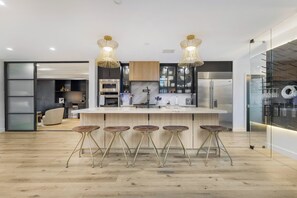 A modern kitchen with a central island, bar stools, and pendant lighting.