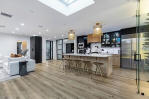 A modern kitchen with a central island, bar stools, and a glass-fronted refrigerator. - Erwin Estate (Woodland Hills)