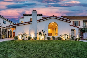 A modern house with a well-maintained lawn, a chimney, and a large arched window. - Bella Villa (Los Angeles)