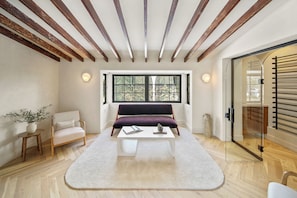 A modern room with a wooden ceiling, a large window, a sofa, a coffee table, and a glass door. - Bella Villa (Los Angeles)
