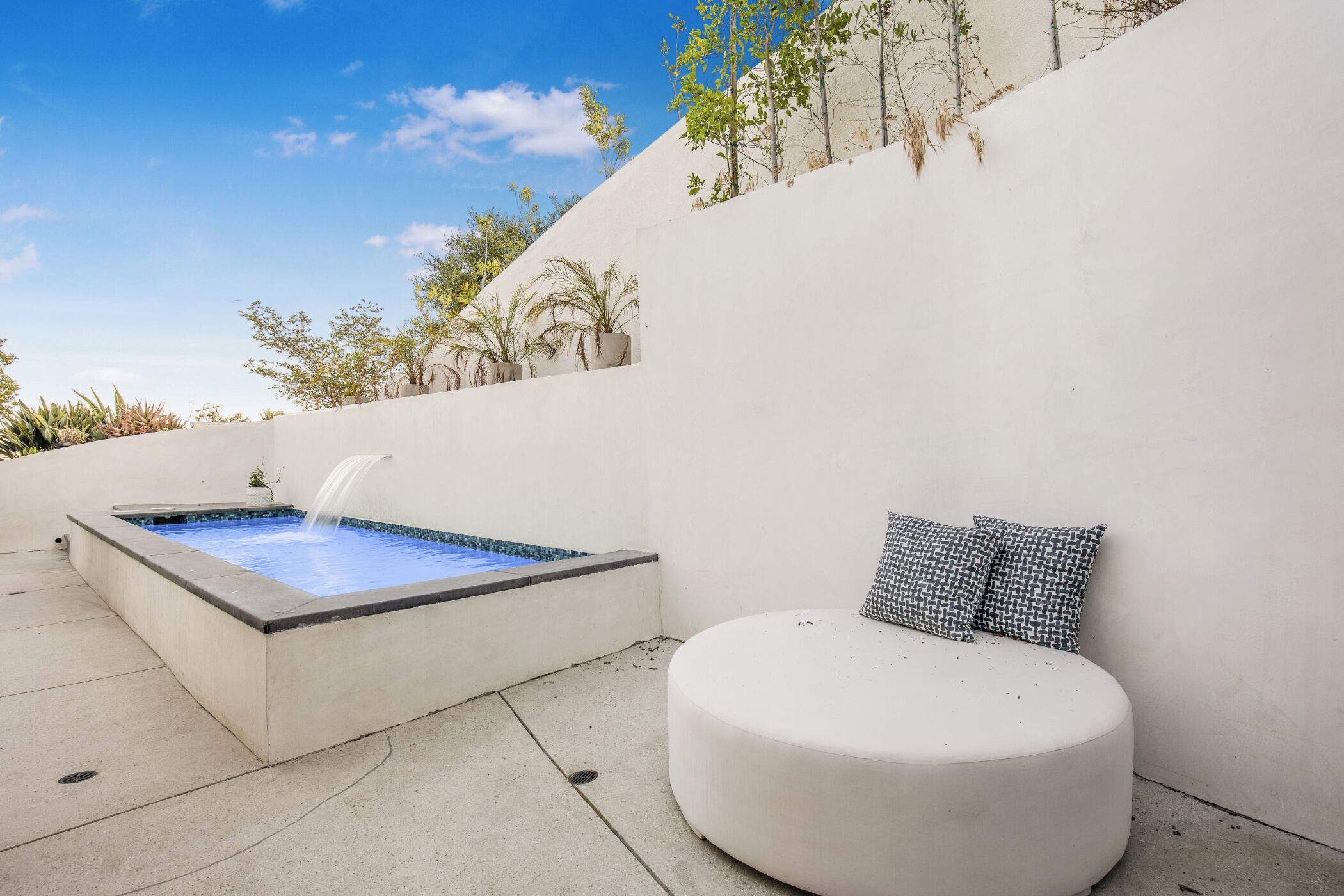 A spa area with a hot tub and a seating area with cushions.