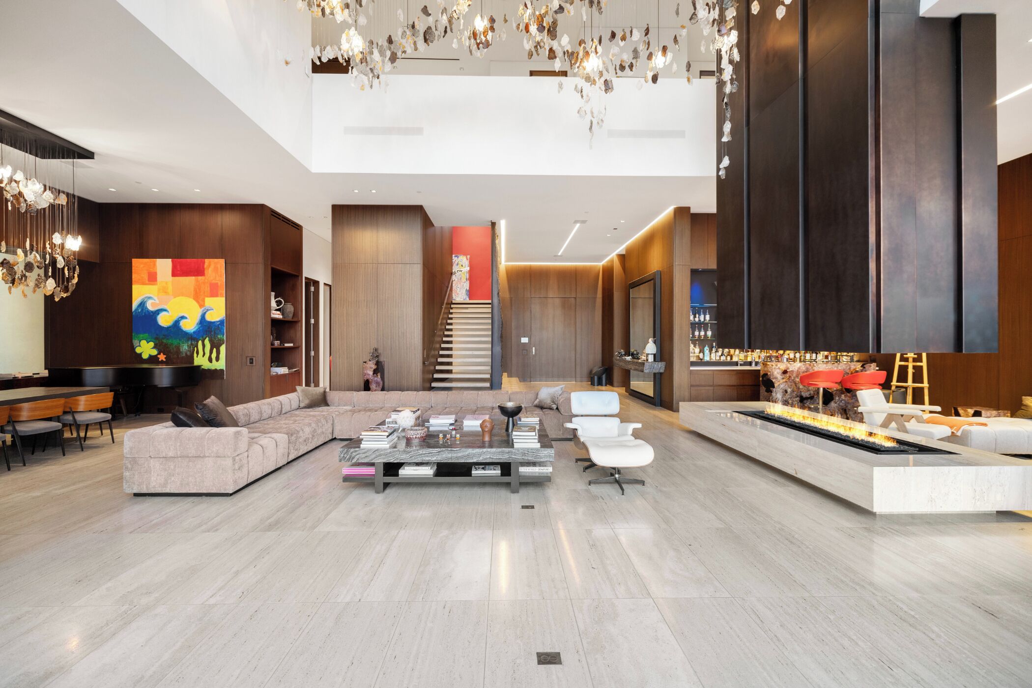 Um hall amplo com design moderno, apresentando uma grande área de estar, uma lareira e uma escadaria para um andar superior.