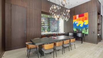 Uma sala de jantar moderna com uma mesa comprida, cadeiras, um candelabro e uma grande pintura abstrata.