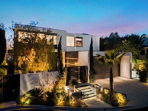 A modern two-story house with a staircase leading to the entrance, surrounded by landscaped gardens and trees. - Collingwood (West Hollywood)