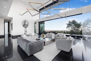 A modern living room with a large window, a gray sofa set, and a coffee table. - London Dream (West Hollywood)