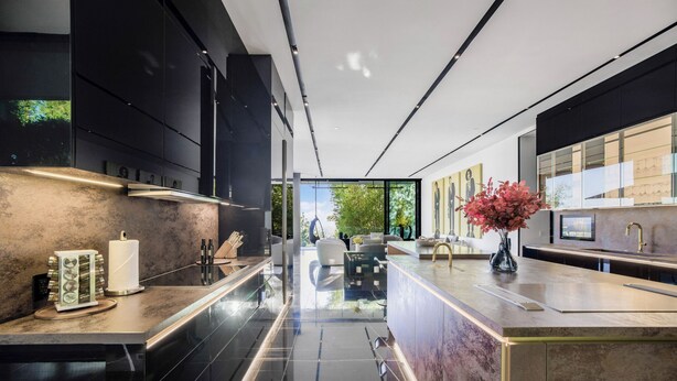 A modern kitchen with black cabinetry, a marble countertop, and a view of the outdoors. - London Dream (West Hollywood)