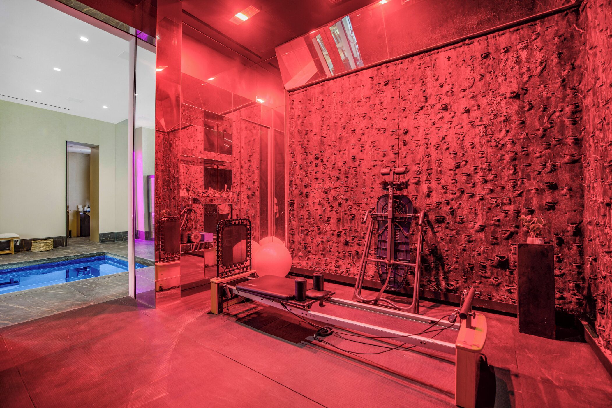 Une pièce avec un mur éclairé en rouge, une table de massage et une petite piscine.
