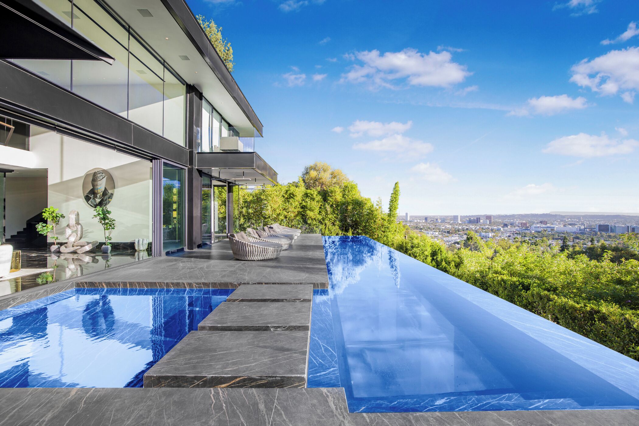 Ein modernes Haus mit Swimmingpool und Sitzgelegenheit im Freien.