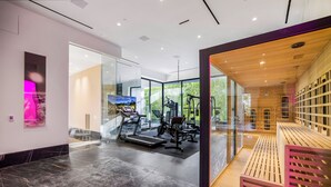 A modern gym with exercise equipment, a large mirror, and a sauna area. - London Dream (West Hollywood)