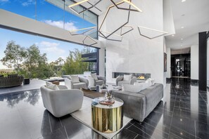 A modern living room with a large sofa, a coffee table, and a fireplace. - London Dream (West Hollywood)