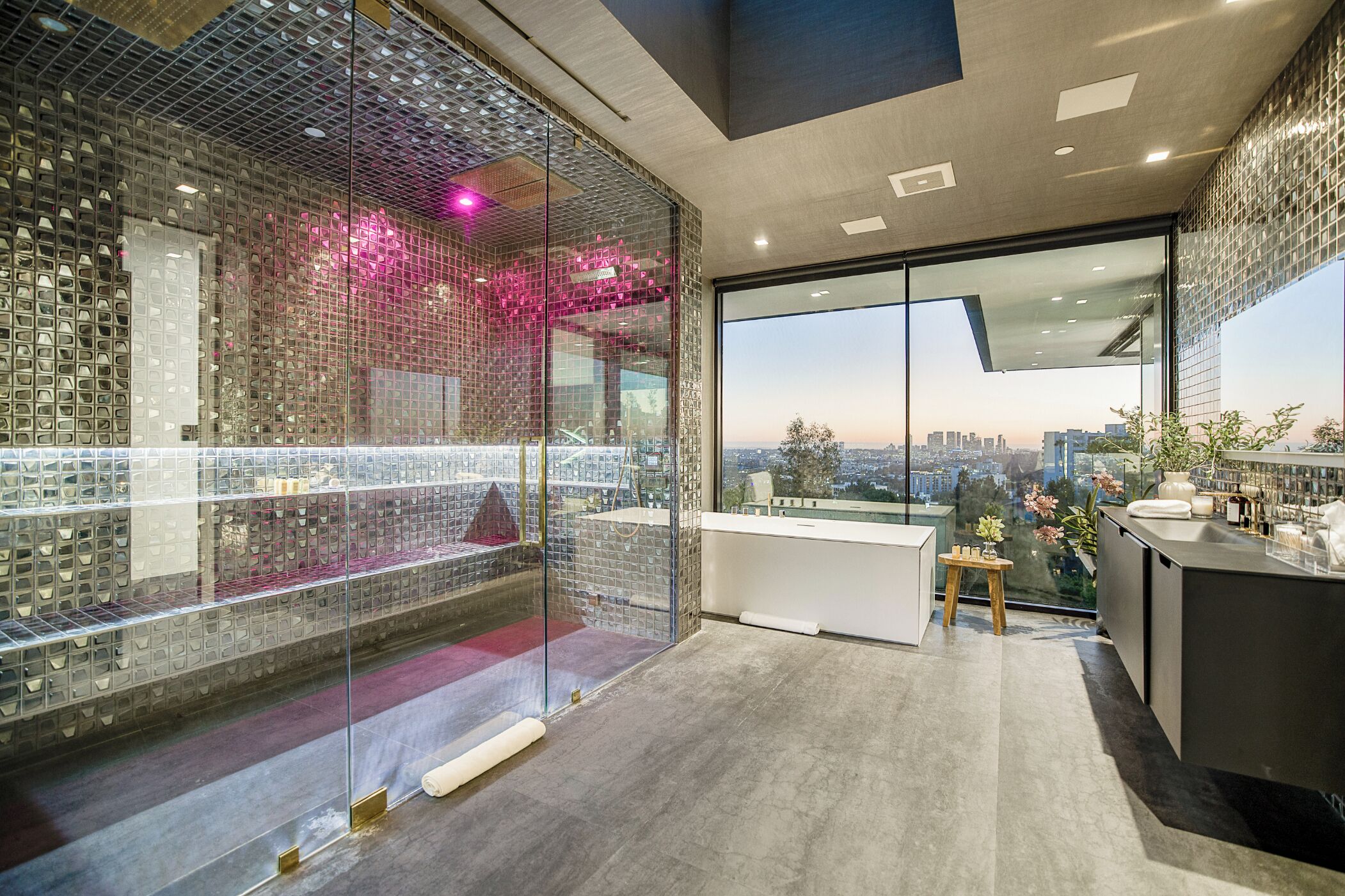 A modern interior with a glass wall, a kitchen area, and a view of the cityscape.
