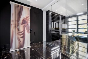 A modern interior with a glass partition, a dark wall with a vertical design, and a reflective floor. - London Dream (West Hollywood)