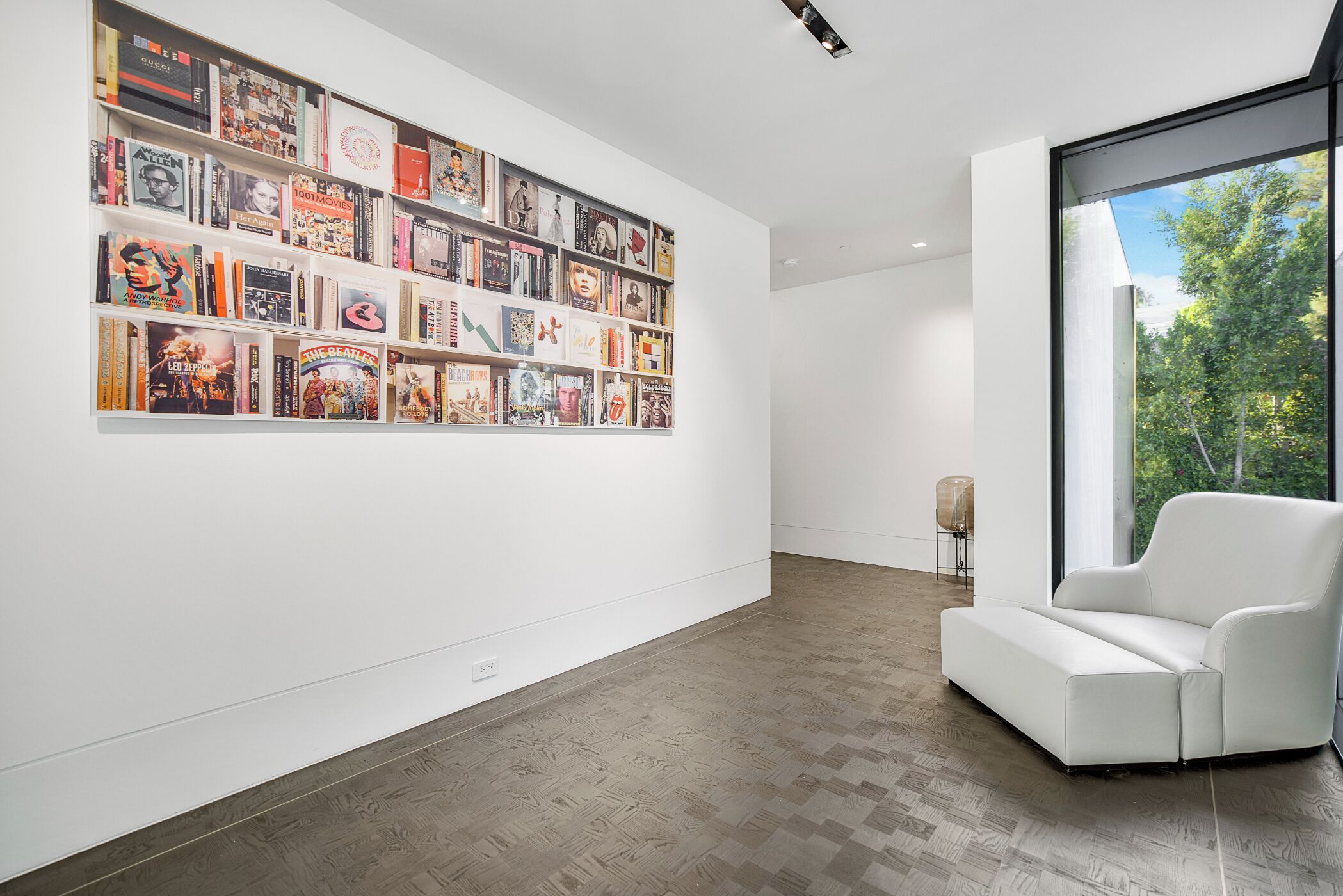 A modern gallery with a white wall and a large collection of books and art.