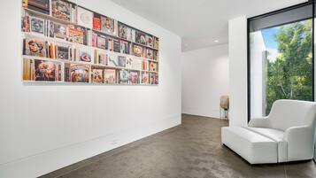A modern gallery with a white wall and a large collection of books and art.