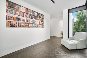A modern gallery with a white wall and a large collection of books and art. - London Dream (West Hollywood)