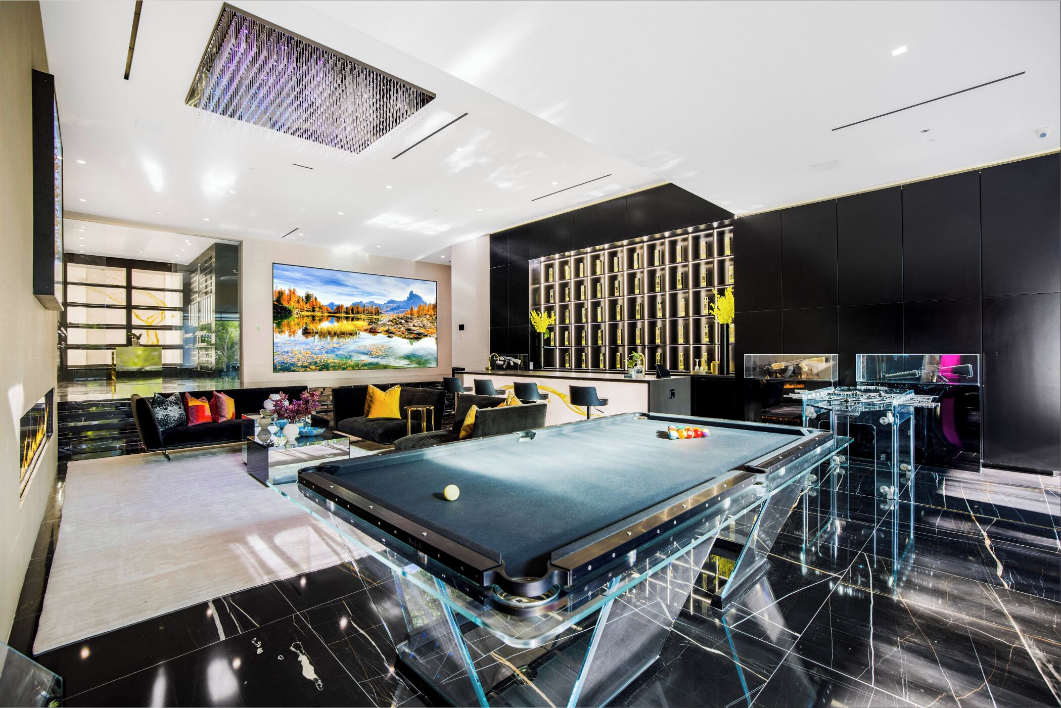 Un área de piscina interior moderna con una mesa de vidrio, decoración en blanco y negro y un cuadro grande de un paisaje.