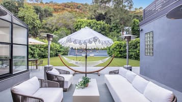 An outdoor seating area with wicker sofas, a central table with a plant, and a hammock.