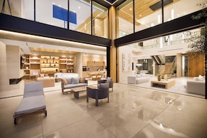 Eine großzügige Lobby mit hoher Decke, modernen Möbeln und einer Treppe zu einer oberen Ebene.