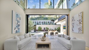 A modern living room with a large sectional sofa, a coffee table, and artwork on the walls. - Hutton Villa (Beverly Hills)