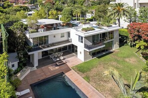 A modern two-story house with a rooftop pool, large glass windows, and a well-maintained garden. - Alta Royale (West Hollywood)