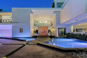 Una casa moderna con piscina, puerta de madera y candelabro.