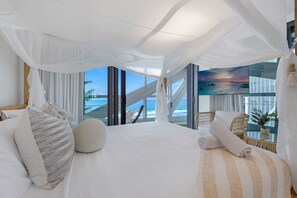 Una camera da letto con un letto grande, vista sull'oceano e un'amaca.