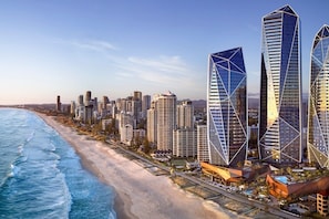 Una città costiera con moderni grattacieli, una spiaggia e un edificio arancione dal design architettonico distintivo.
