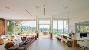 A spacious living area with a large wooden table, comfortable seating, and a view of the outdoors. - Zen Estate (Beverly Hills)