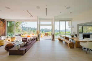 A spacious living area with a large wooden table, comfortable seating, and a view of the outdoors. - Zen Estate (Beverly Hills)