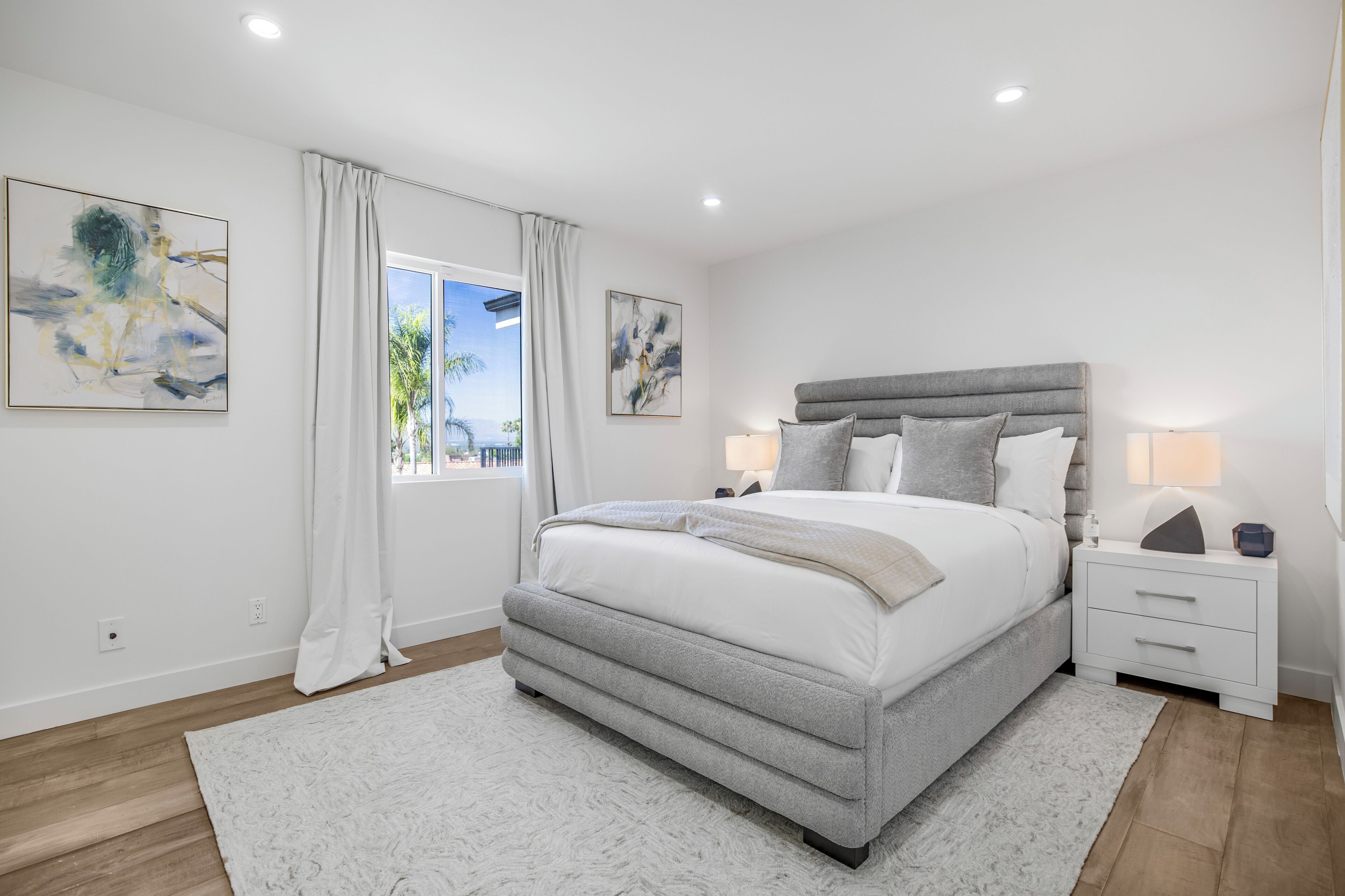A modern bedroom with a large bed, bedside tables, and artwork on the walls.