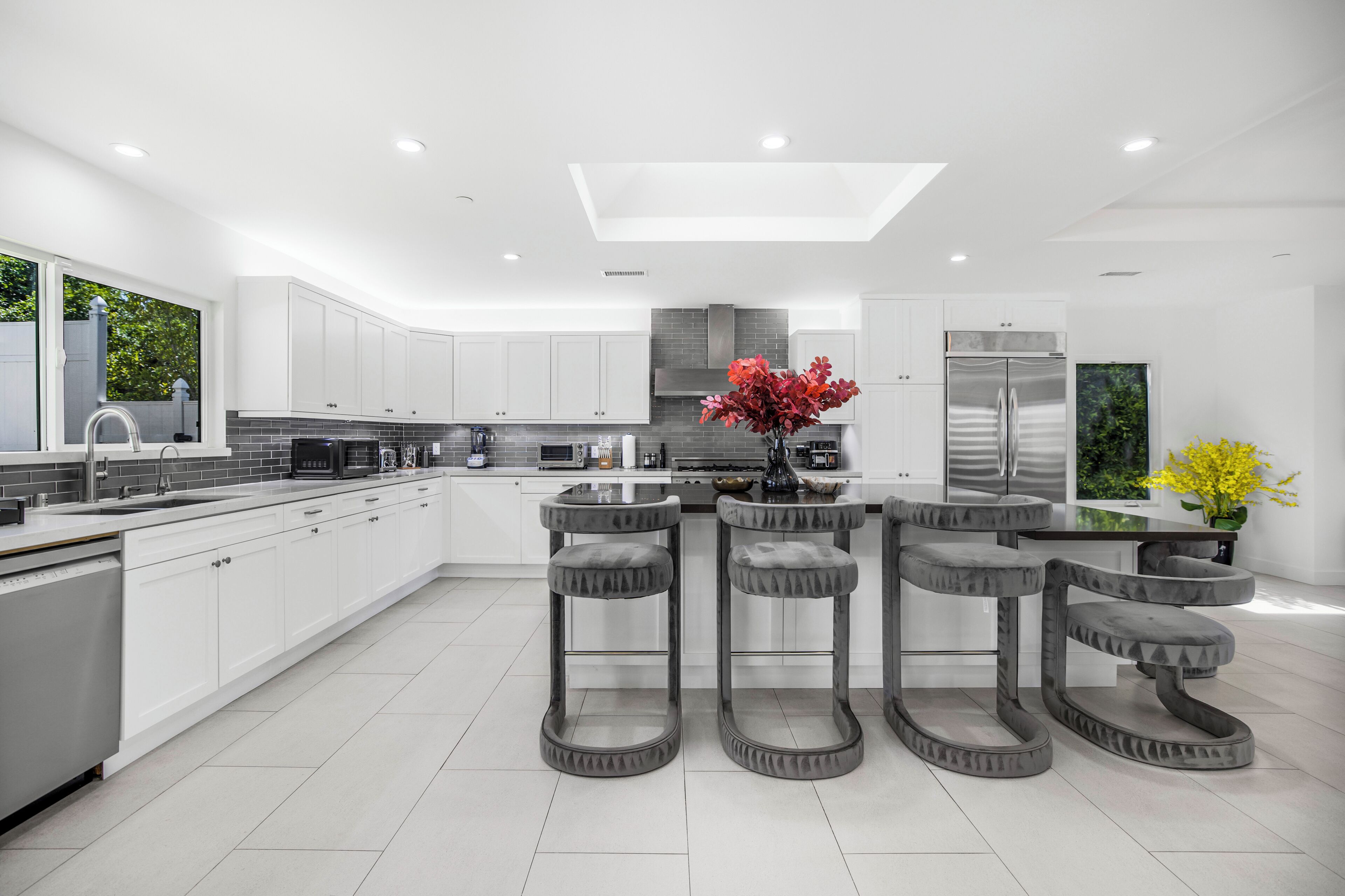 A modern kitchen with white cabinets, a central island, and bar stools.